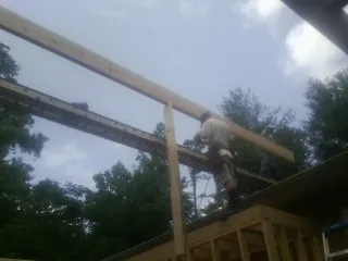 Carpenter setting a ridge beam over a new addition frame — Ice Dam Removal by Roofing Brothers in Casco