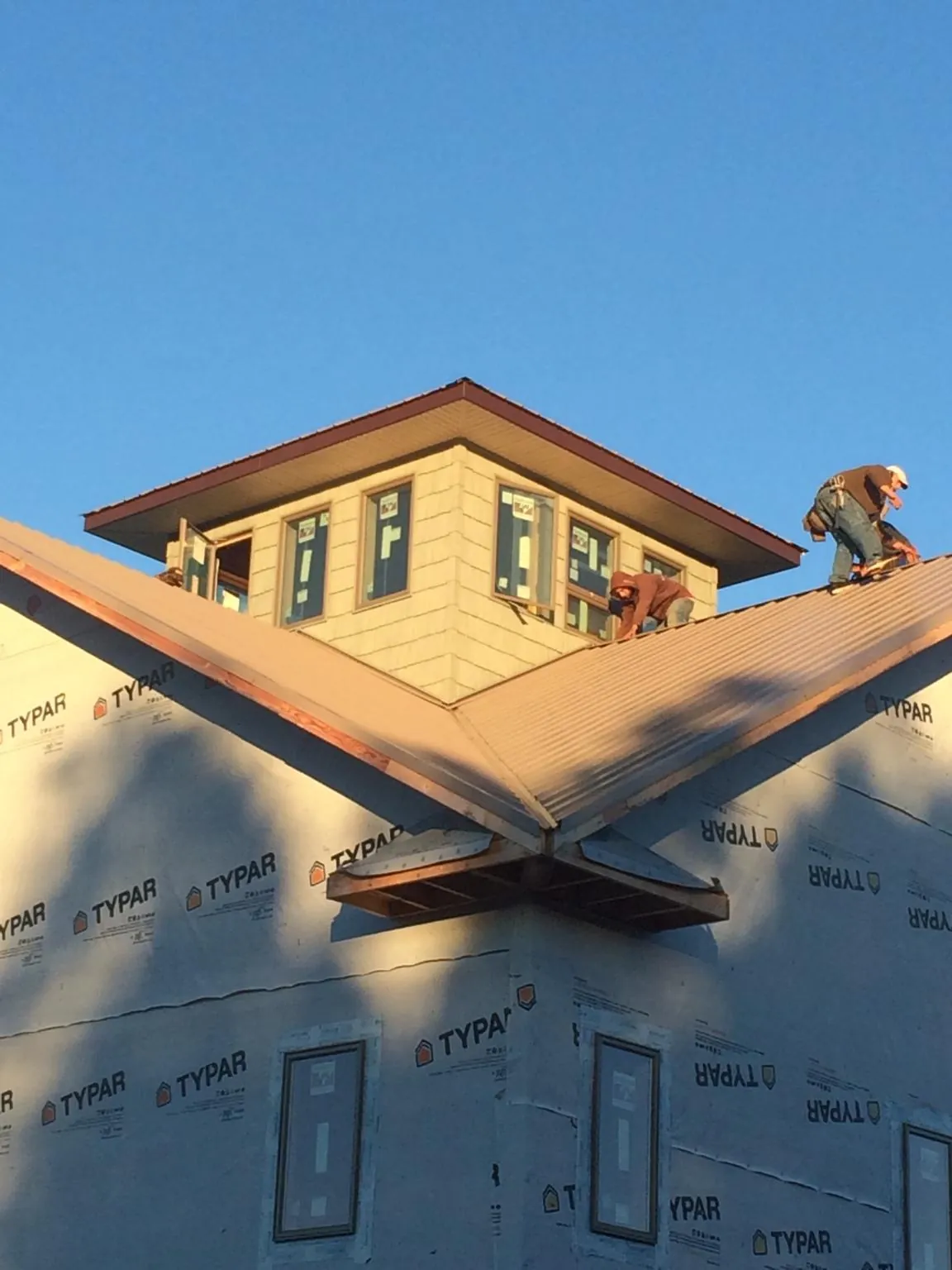 Roofers working around a rooftop cupola on a new metal roof at sunset — Roof Waterproofing in Casco by Roofing Brothers